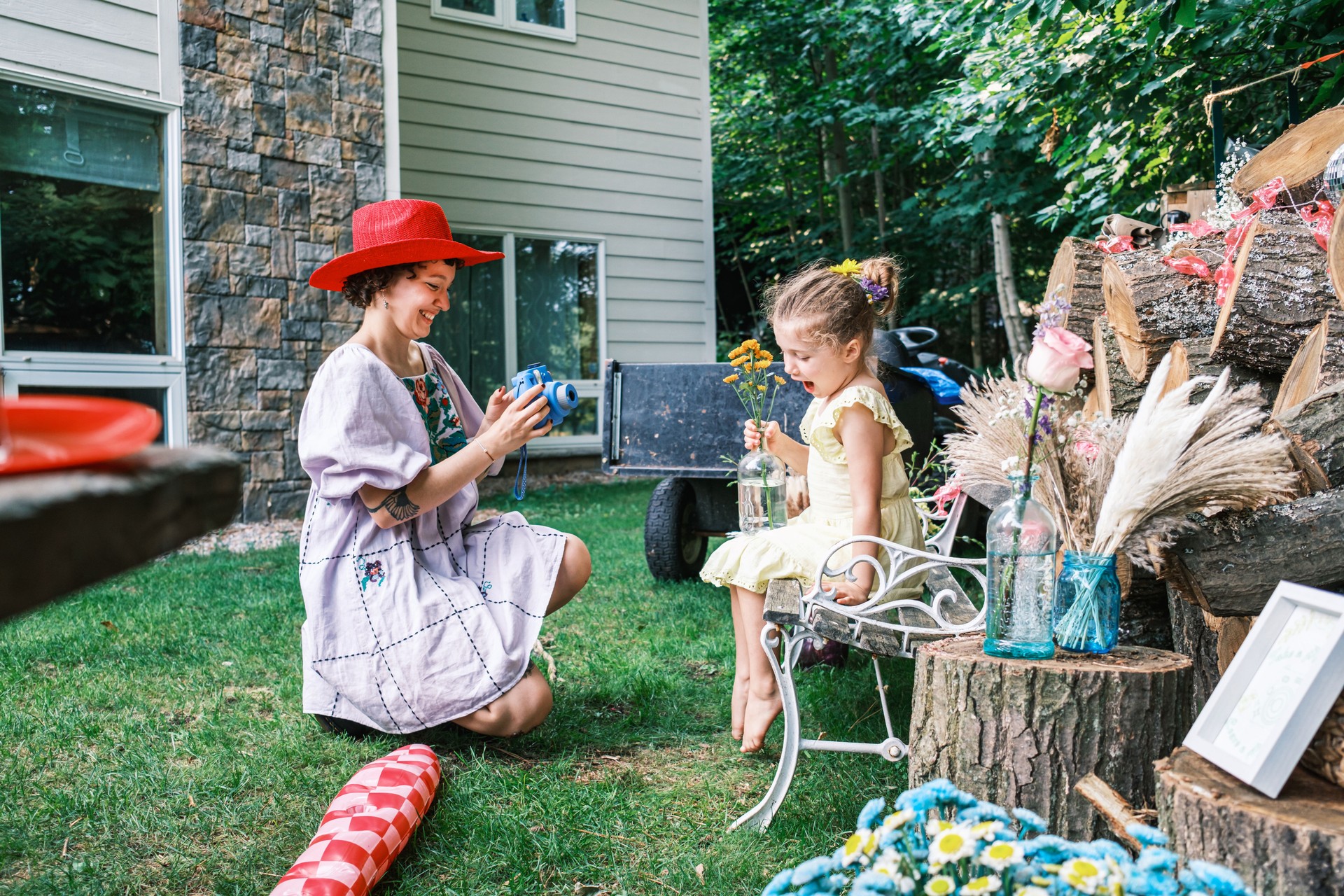 Young woman and little girl taking instant photos at the outdoor wedding party